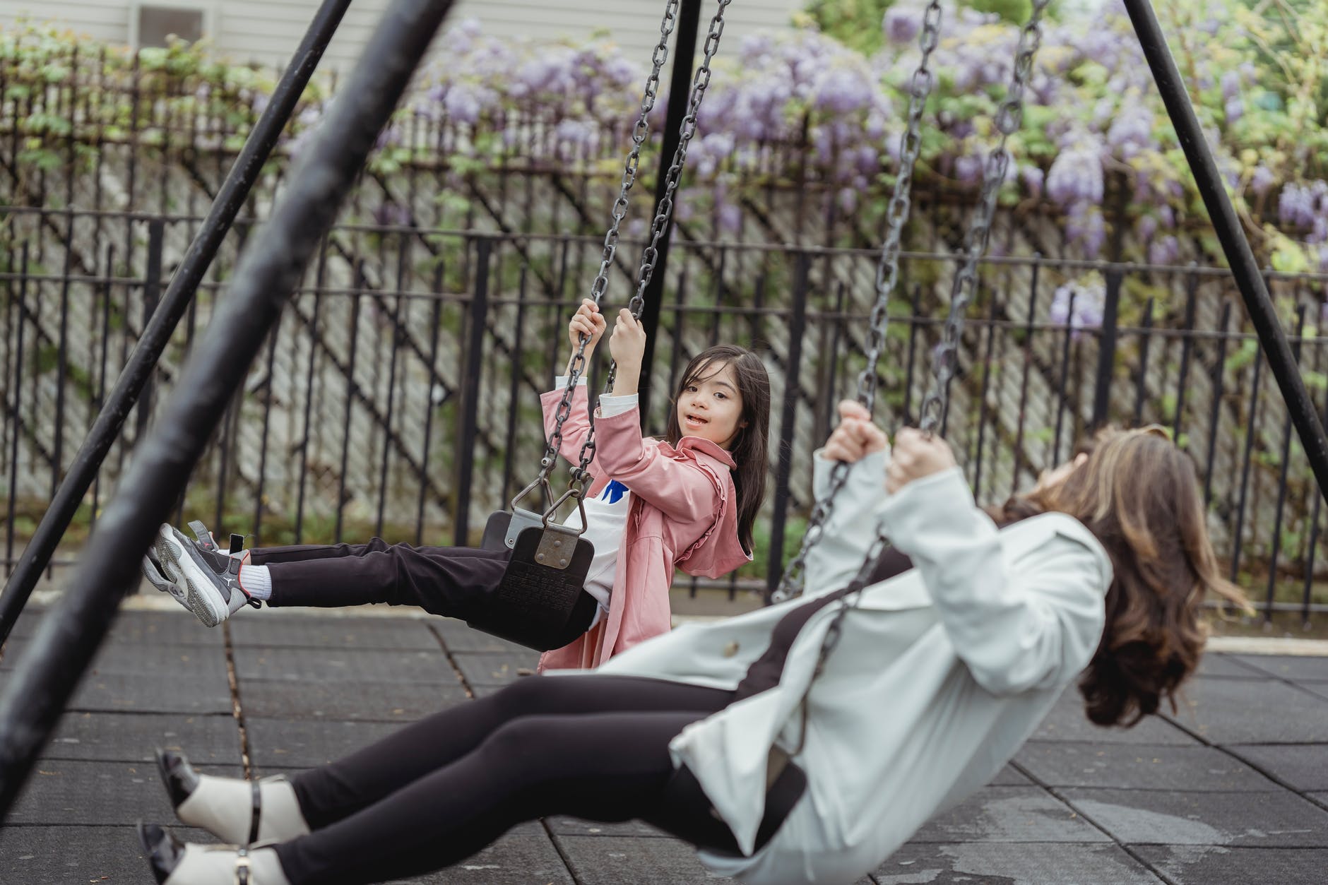 a woman and a young girl playing on the swing