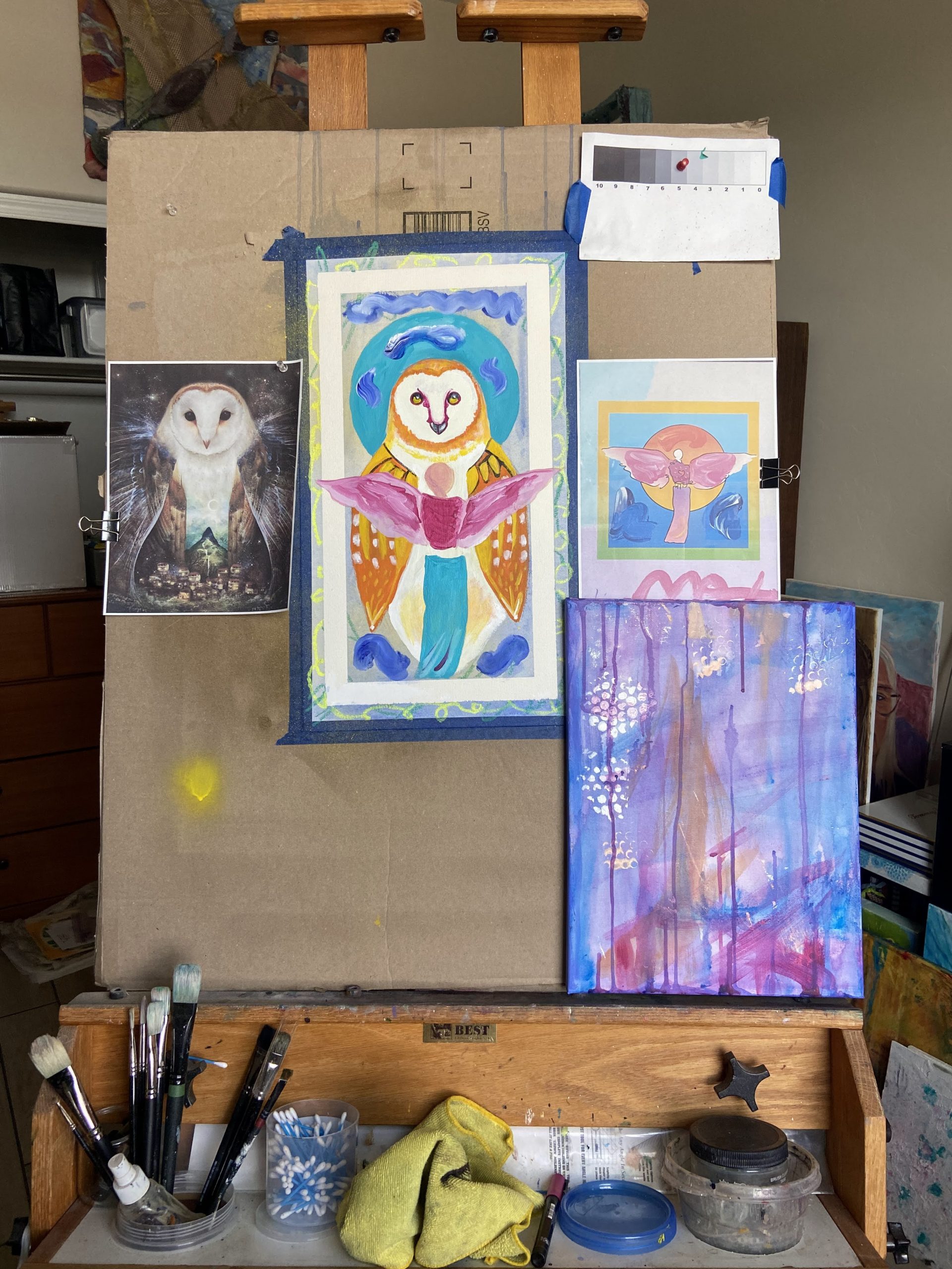 Photo showing an easel with an owl painting and the sources used for reference. 
