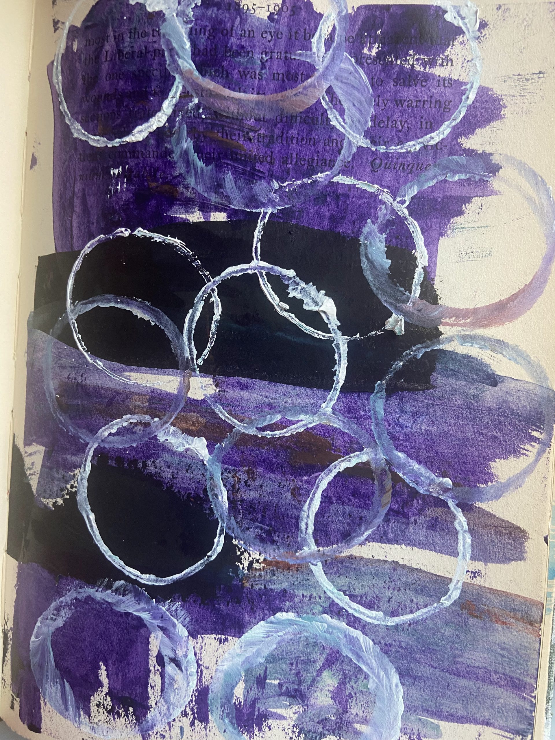 Mark making in an old book done with acrylic paint and using a toilet paper roll to make circles.